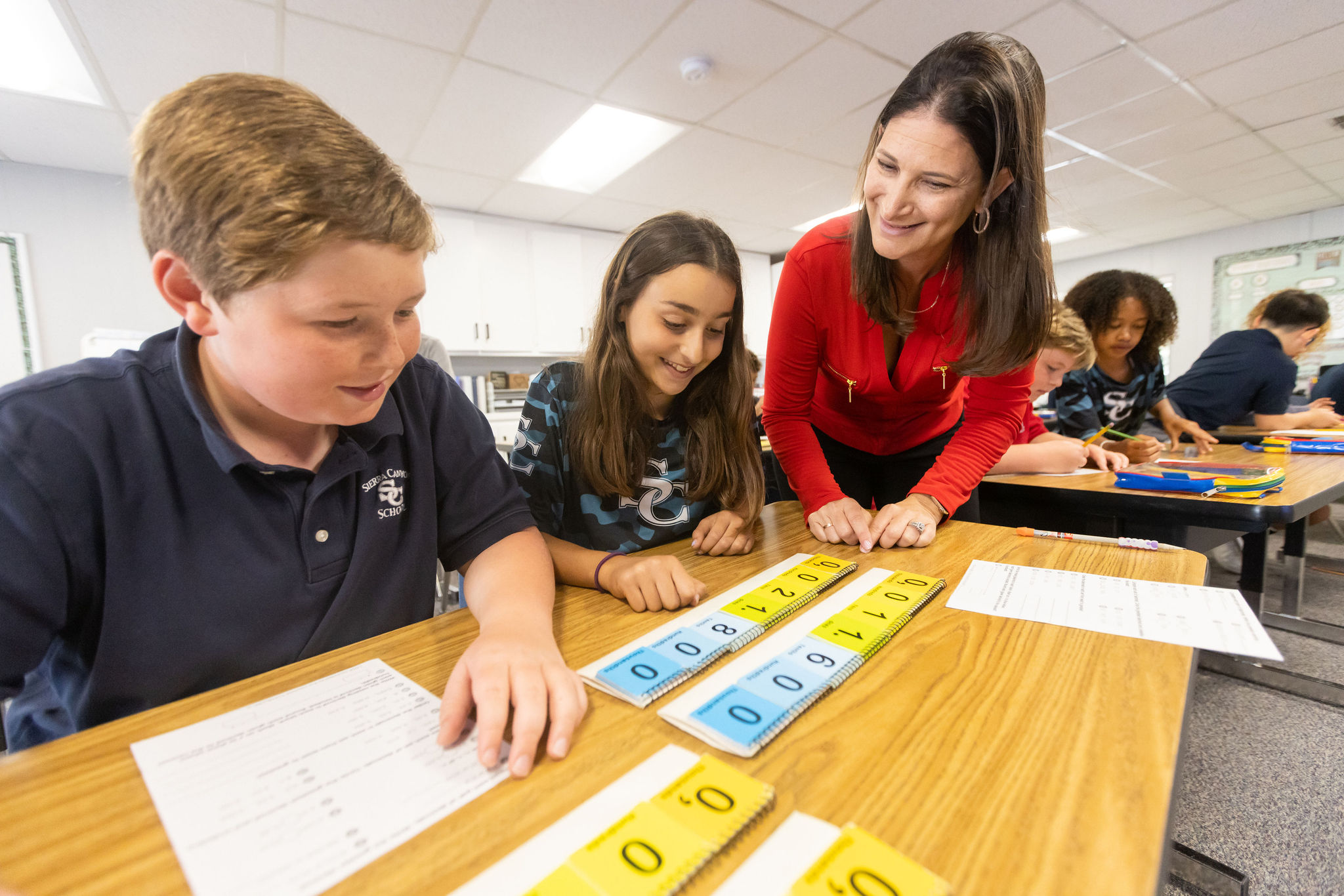 A lower school teacher and two students from Sierra Canyon are working together on a numbers activity.