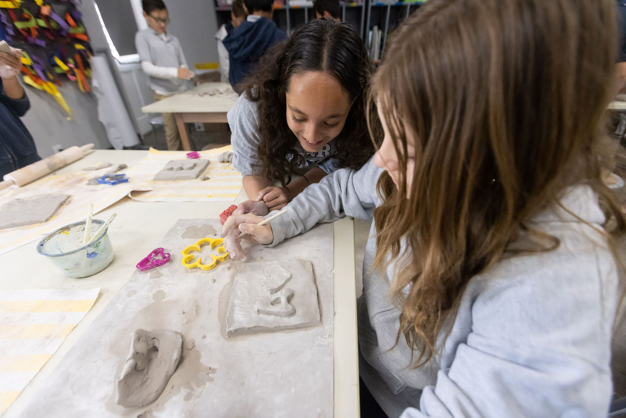 Two girls in a Sierra Canyon visual arts program classroom, creating clay sculptures together.